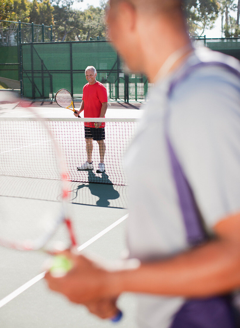 Older men playing tennis on court