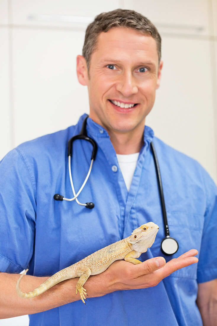 Smiling veterinarian holding lizard