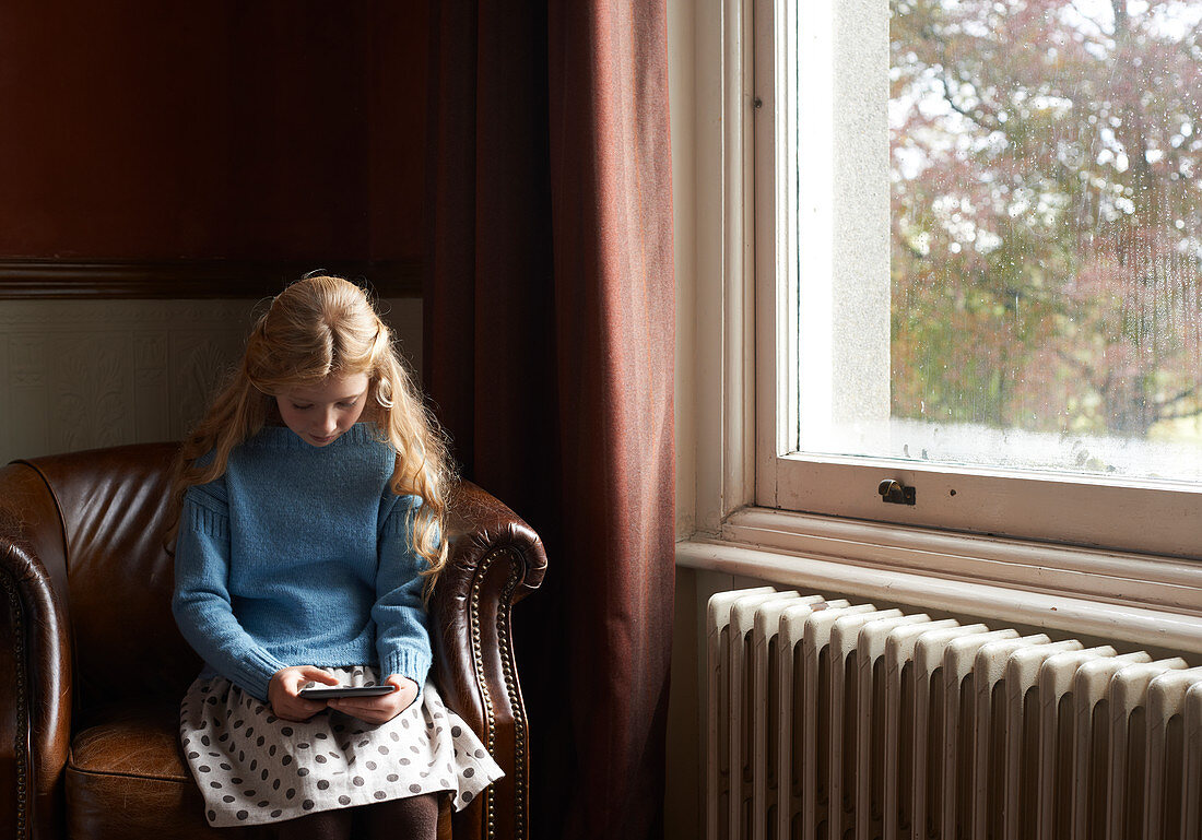 Girl using digital tablet in armchair