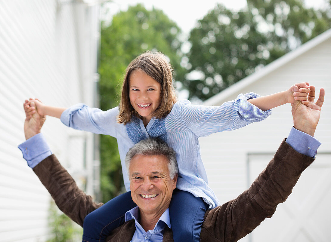 Man carrying granddaughter on shoulders