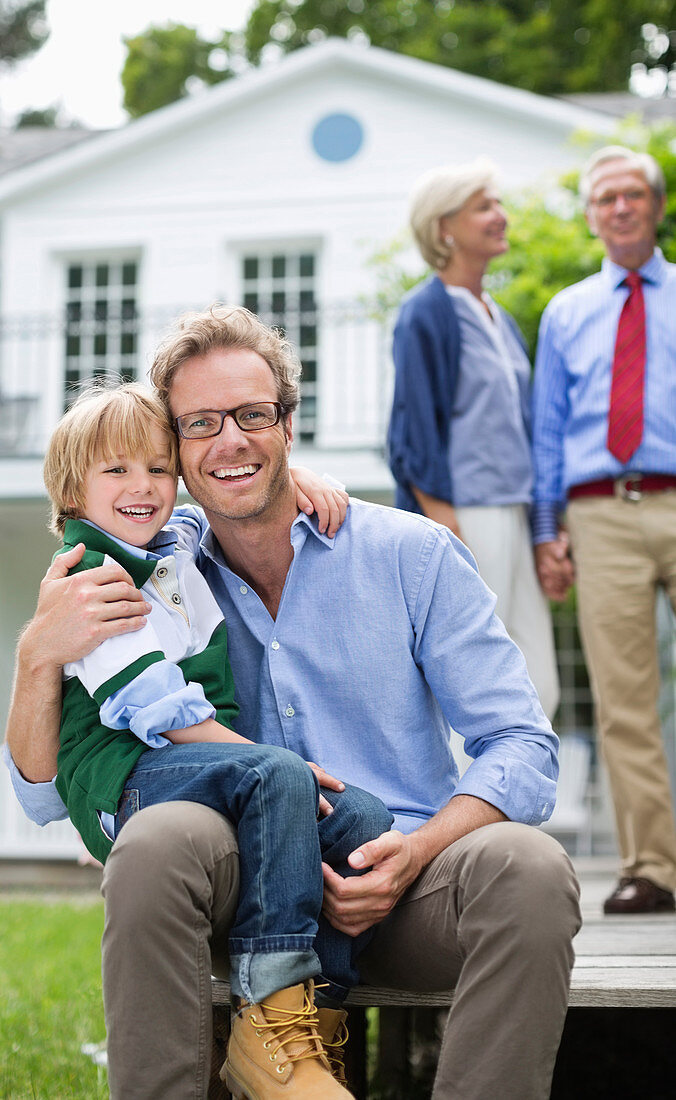 Father and son smiling outside house