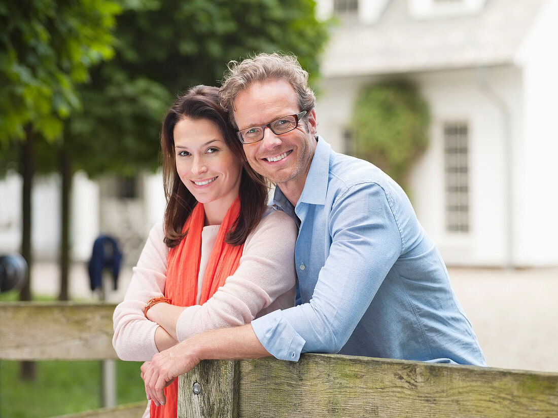 Couple smiling by wooden fence