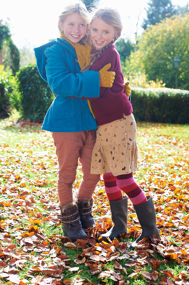 Girls hugging in autumn leaves