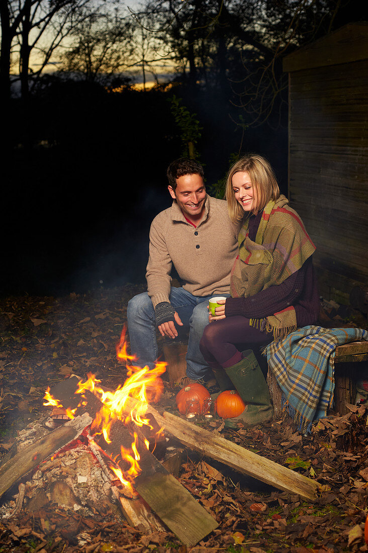 Couple talking around campfire at night