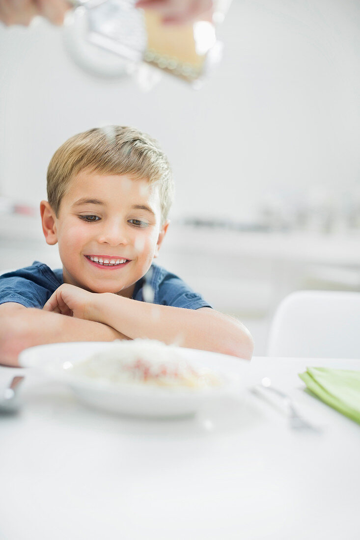 Smiling boy having spaghetti at table