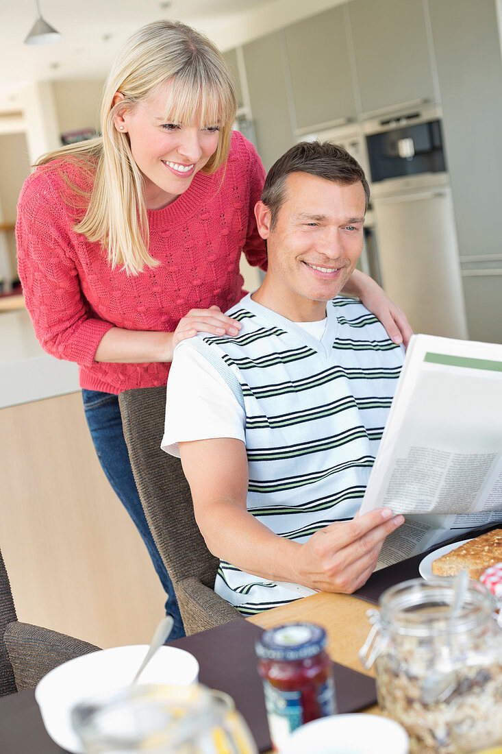 Couple reading newspaper at breakfast