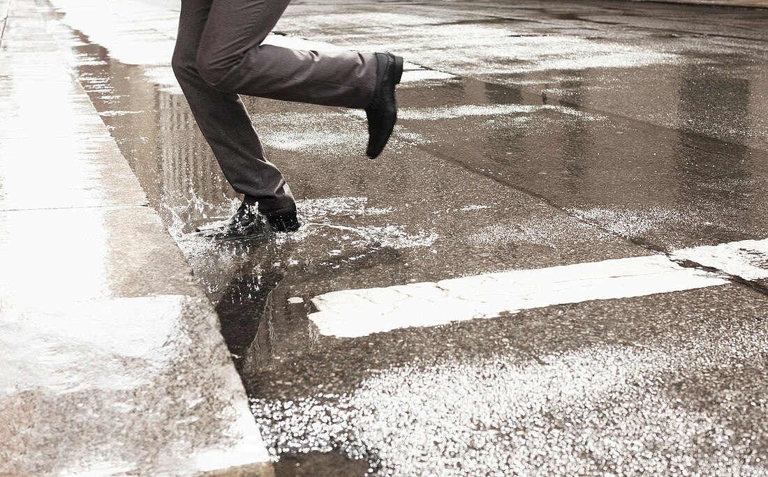 Businessman stepping in puddle