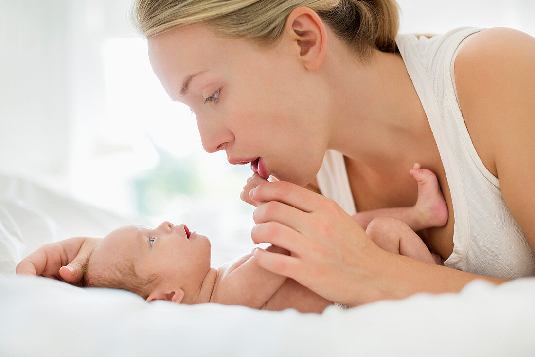 Mother cradling newborn infant on bed