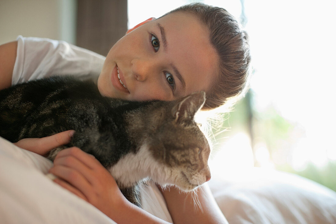 Girl petting cat on bed