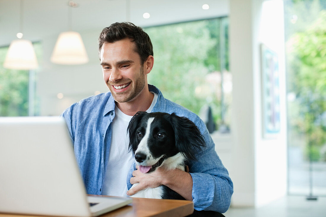Man with dog on lap using laptop