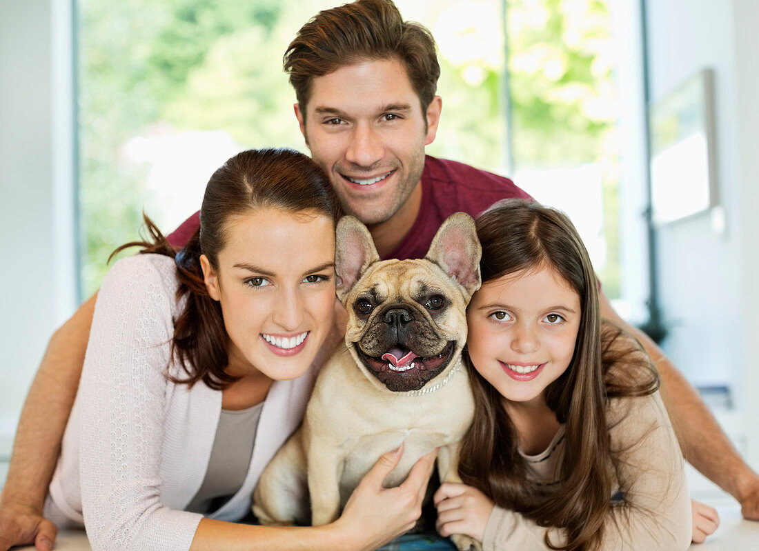 Smiling family hugging dog