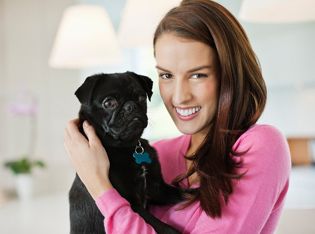 Smiling woman holding dog indoors