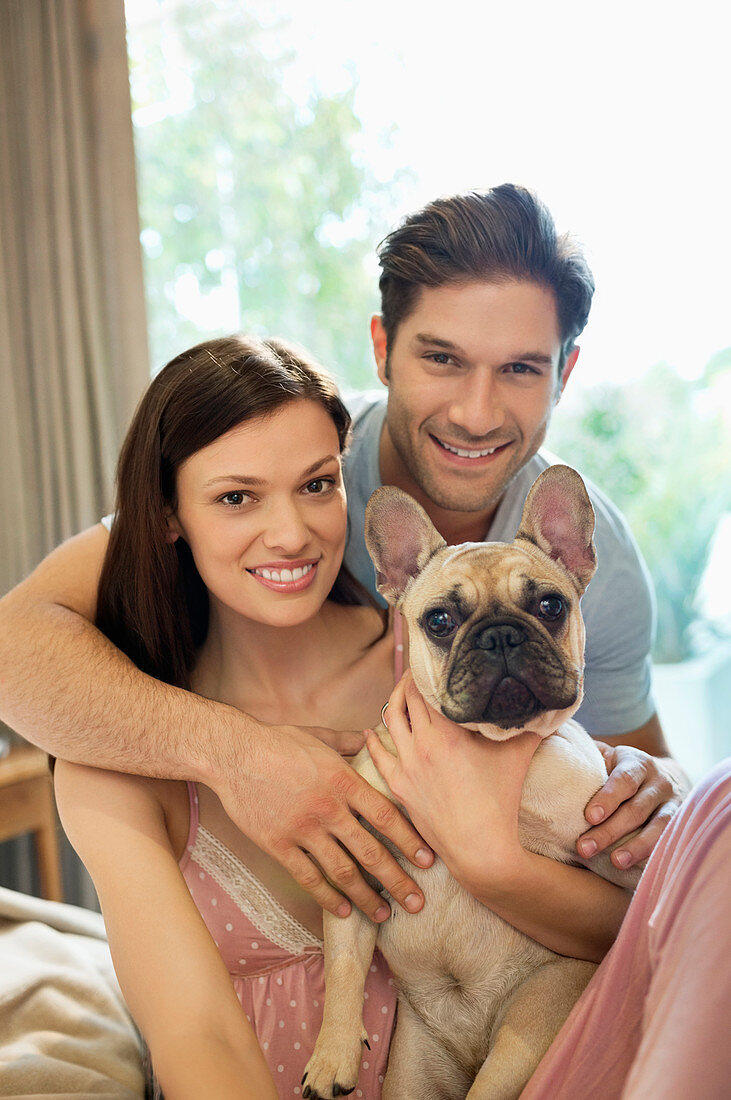 Couple hugging dog on bed