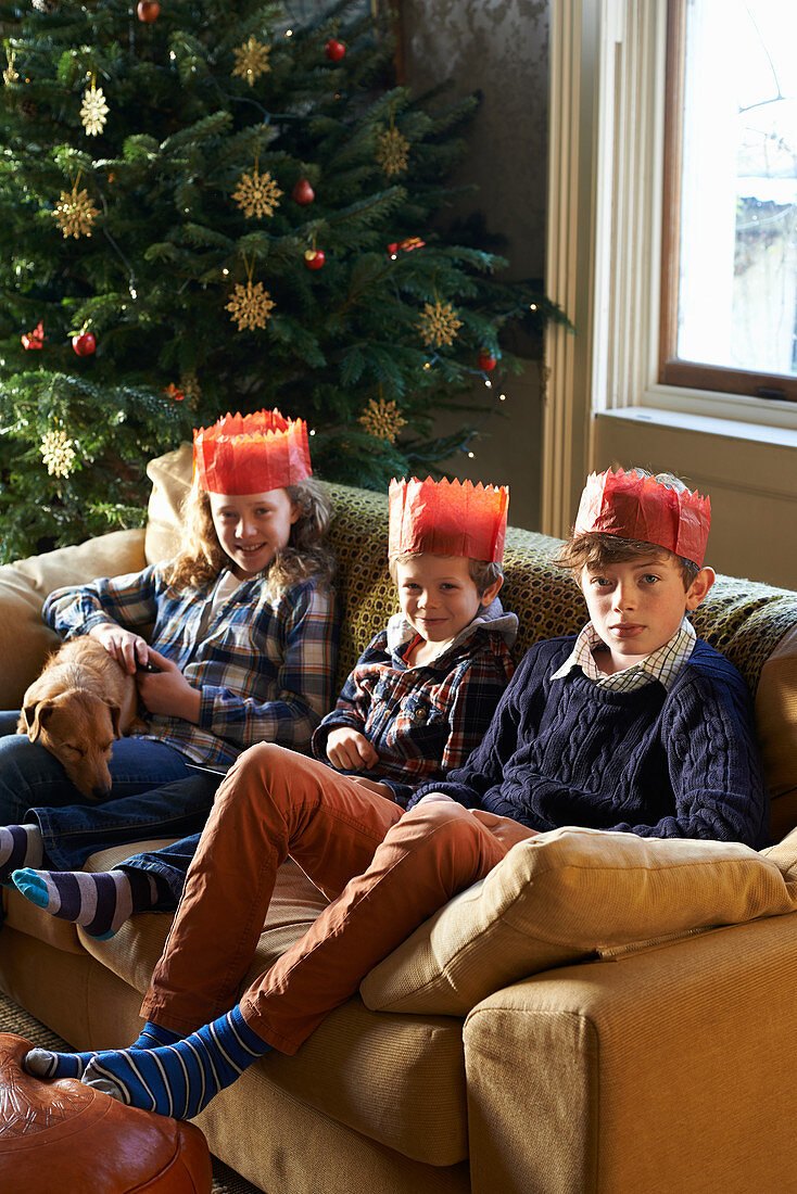 Children in paper crowns sitting on sofa