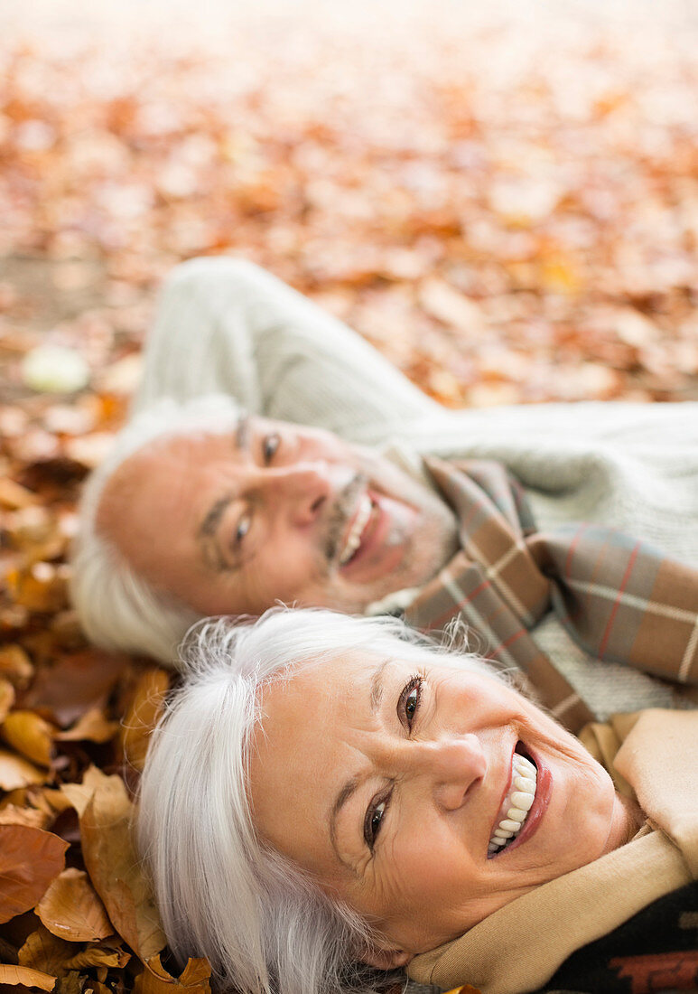 Older couple laying in autumn leaves