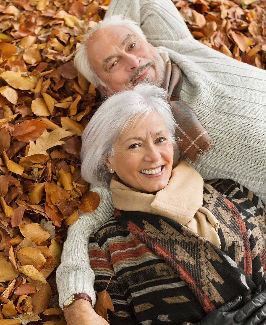 Older couple laying in autumn leaves