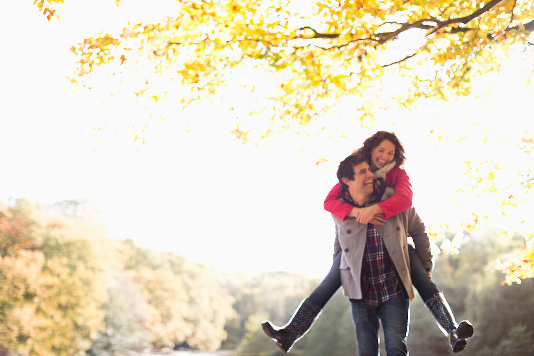 Man carrying girlfriend piggyback in park