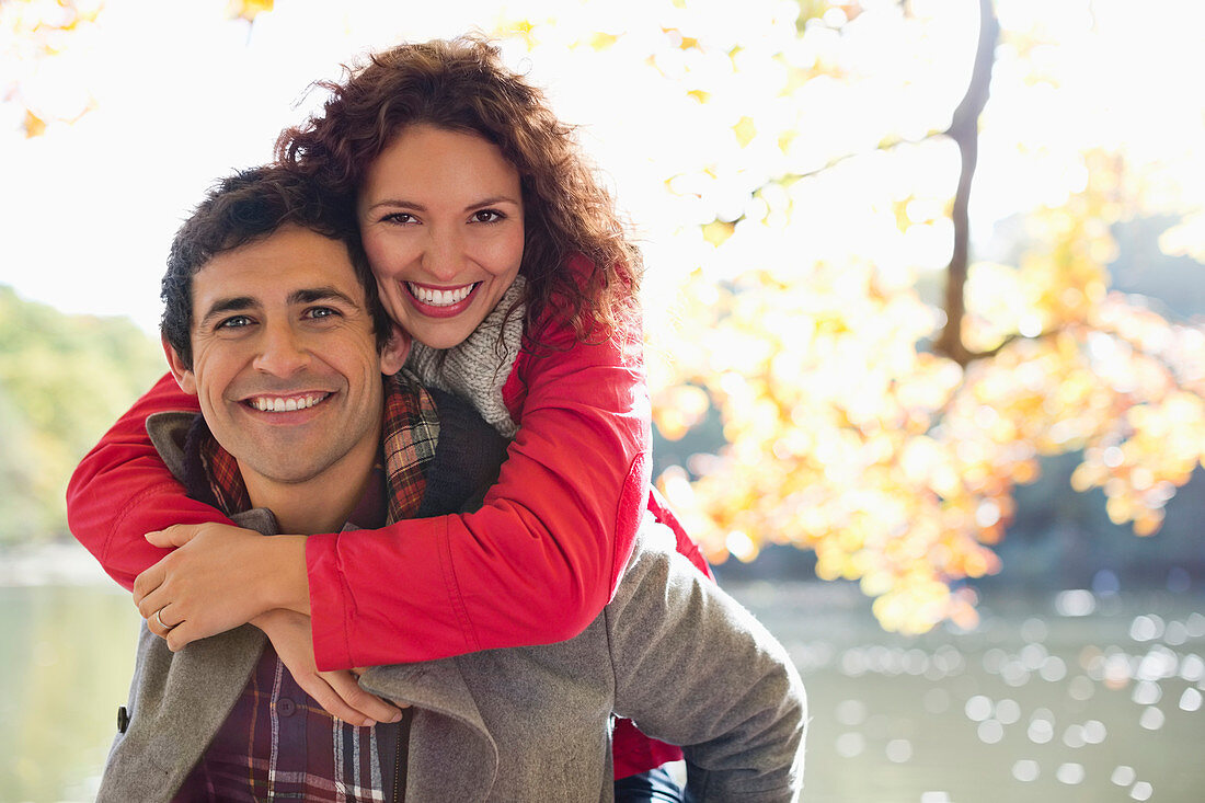 Man carrying girlfriend piggyback in park