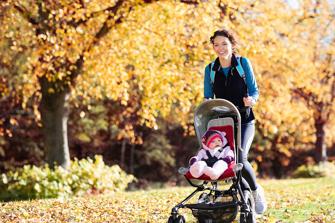 Woman running with baby stroller in park