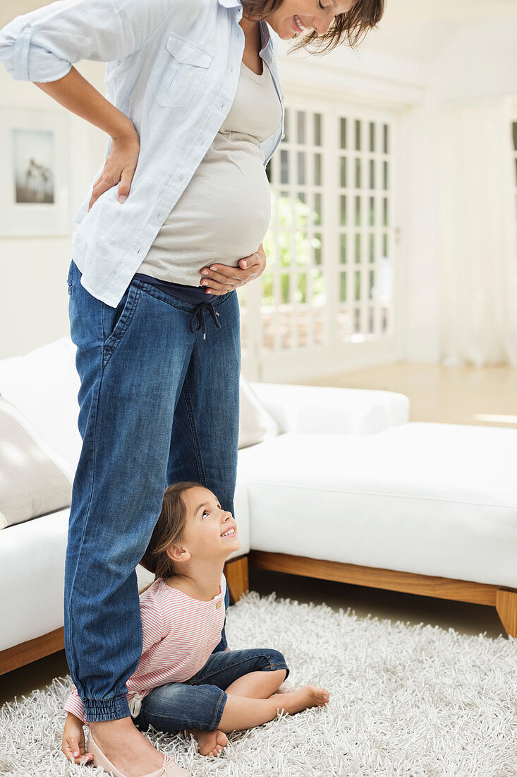 Girl holding pregnant mother's legs