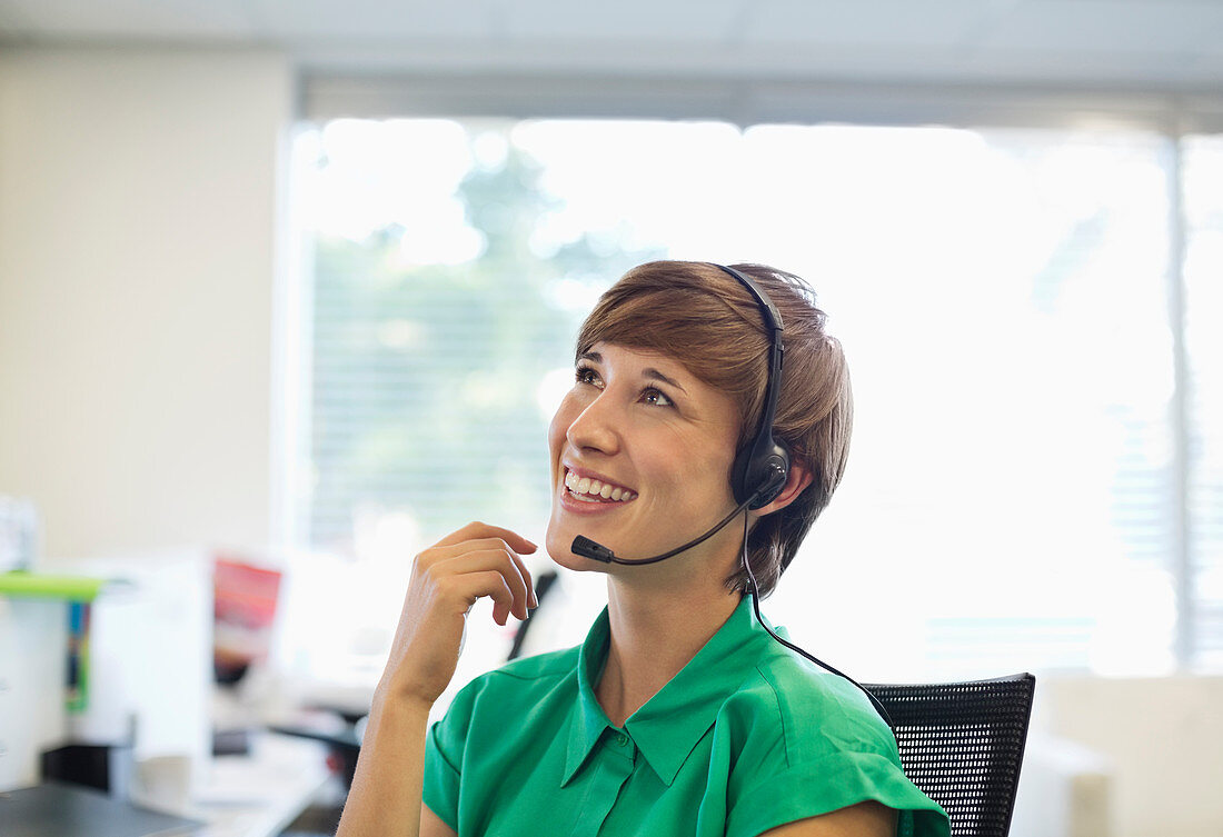 Businesswoman talking on headset at desk