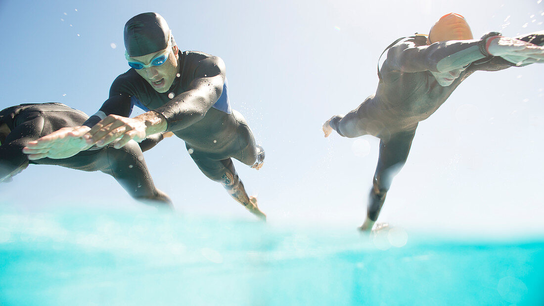 Triathletes in wetsuits diving