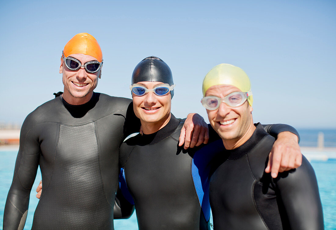 Triathletes in wetsuits smiling together