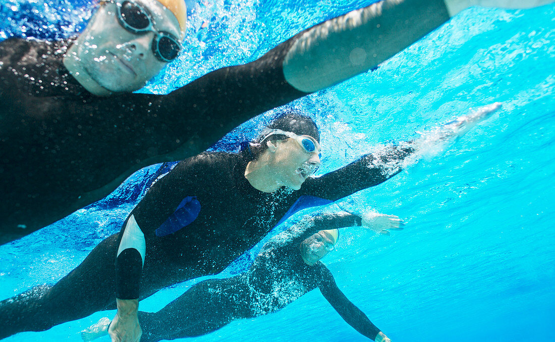 Triathletes in wetsuits underwater