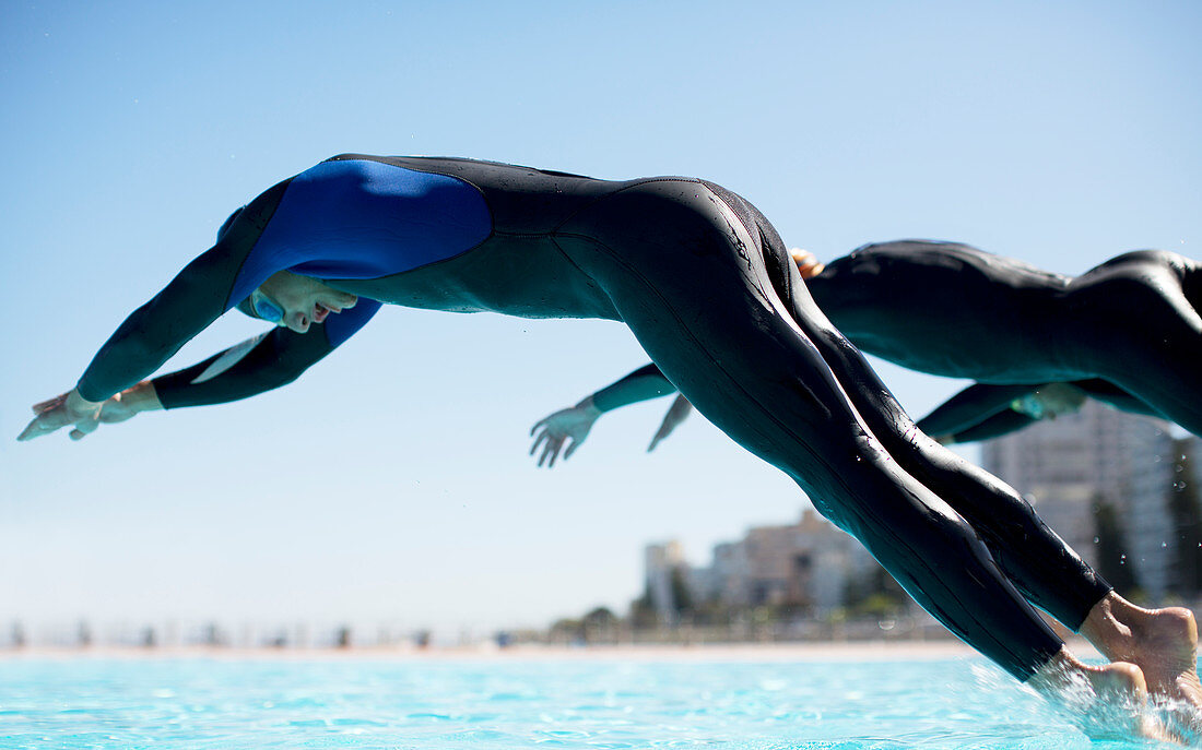 Triathletes diving into swimming pool