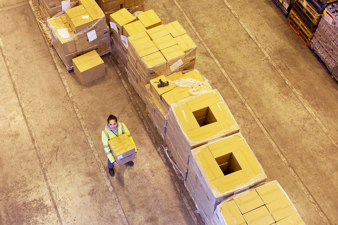 Worker carrying box in warehouse