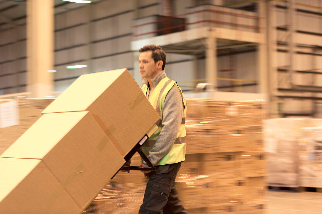 Worker carting boxes in warehouse