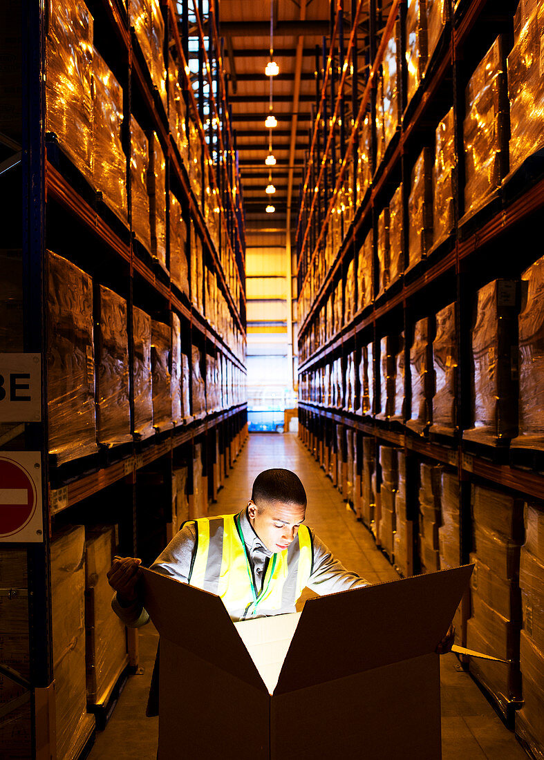 Worker opening glowing box in warehouse