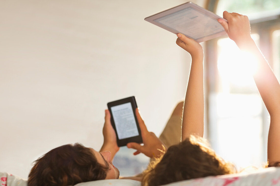 Couple using tablet computers in bed