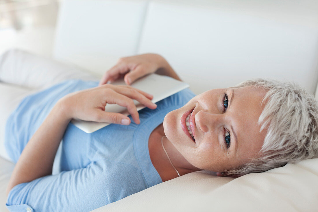 Woman holding tablet computer on sofa