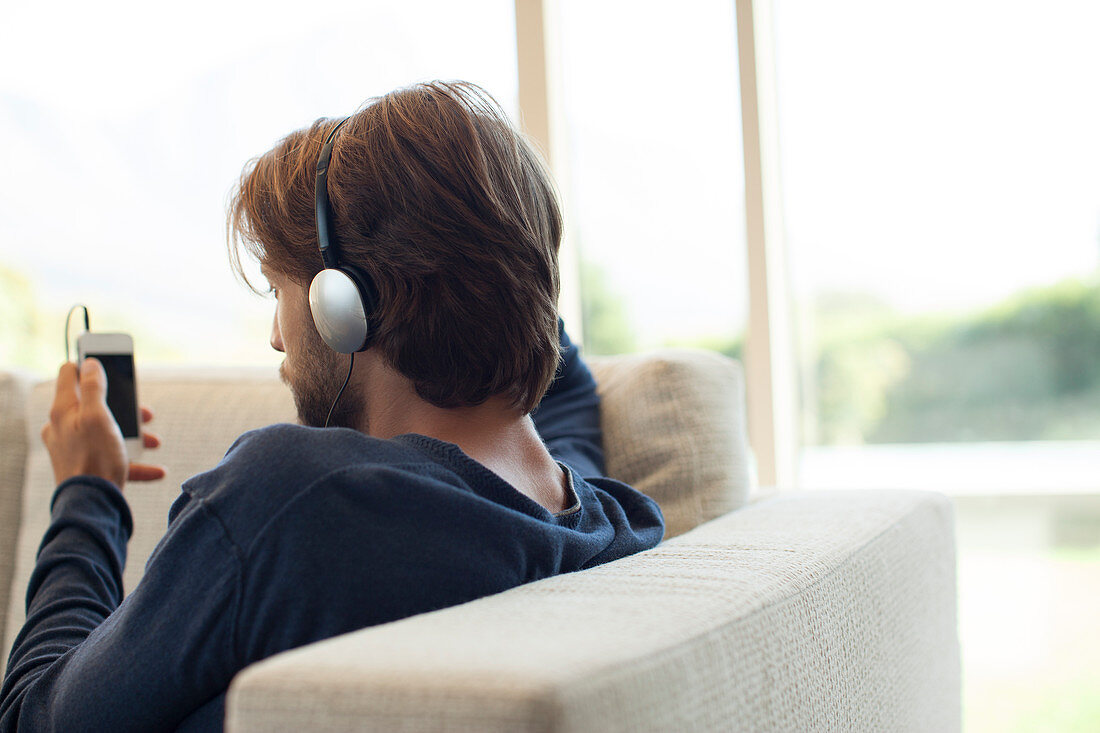 Man listening to headphones on sofa