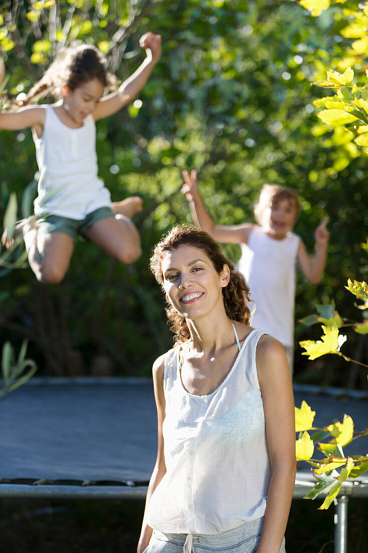 Mother standing by children on trampoline
