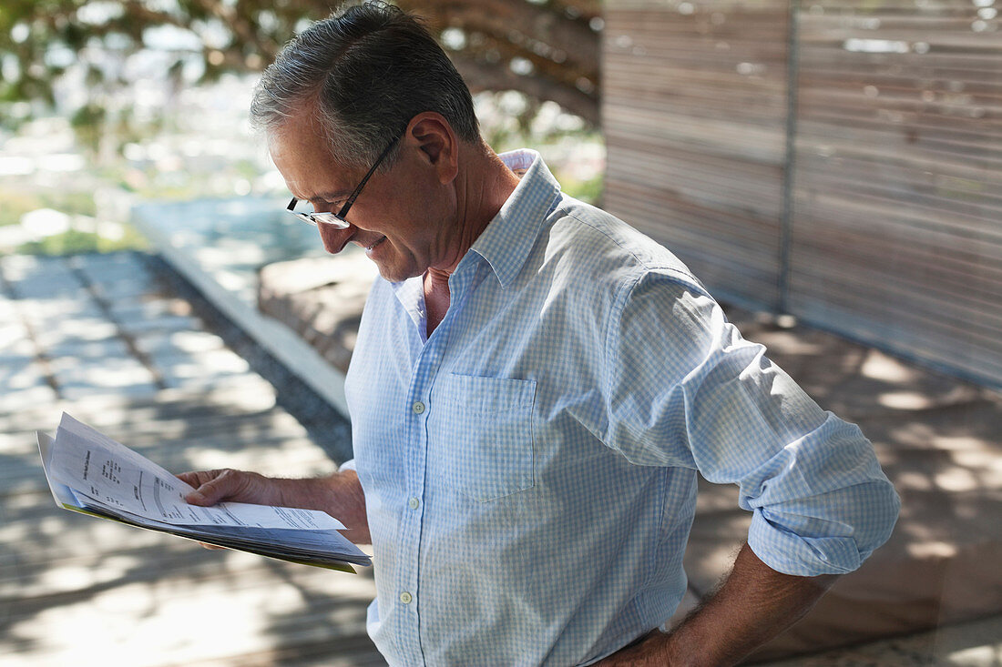 Businessman reading papers outdoors