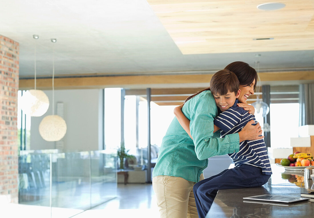 Mother hugging son in kitchen