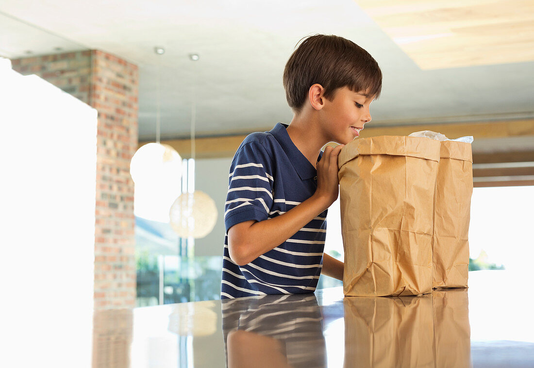 Boy looking through paper bag in kitchen