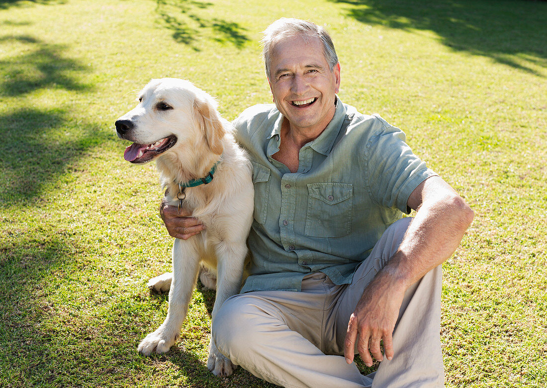 Older man hugging dog in backyard