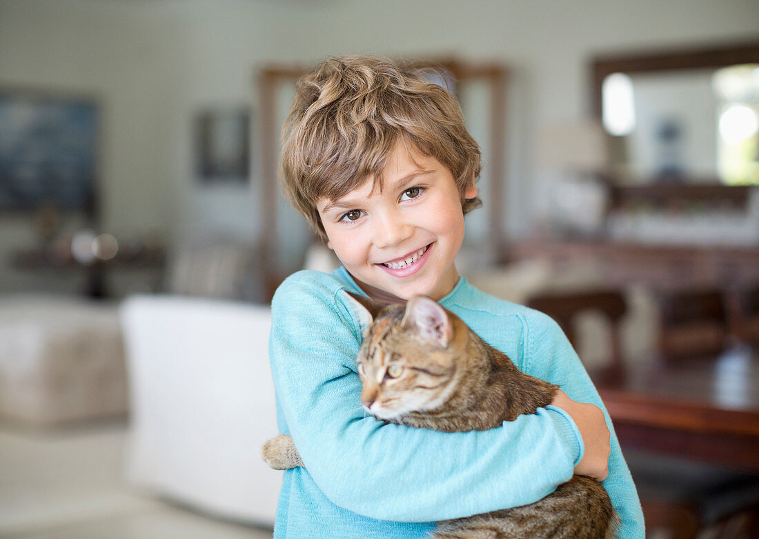 Boy hugging cat in living room