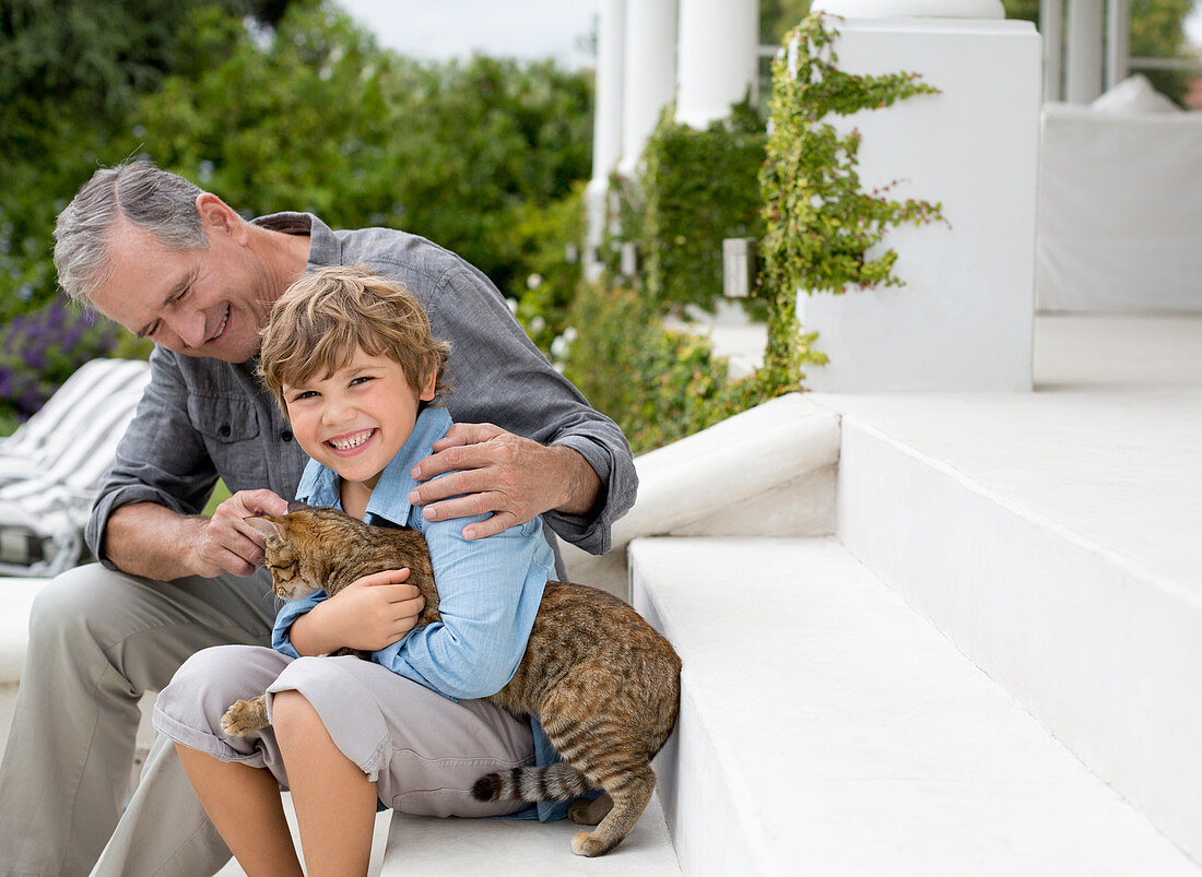 Older man and grandson petting cat