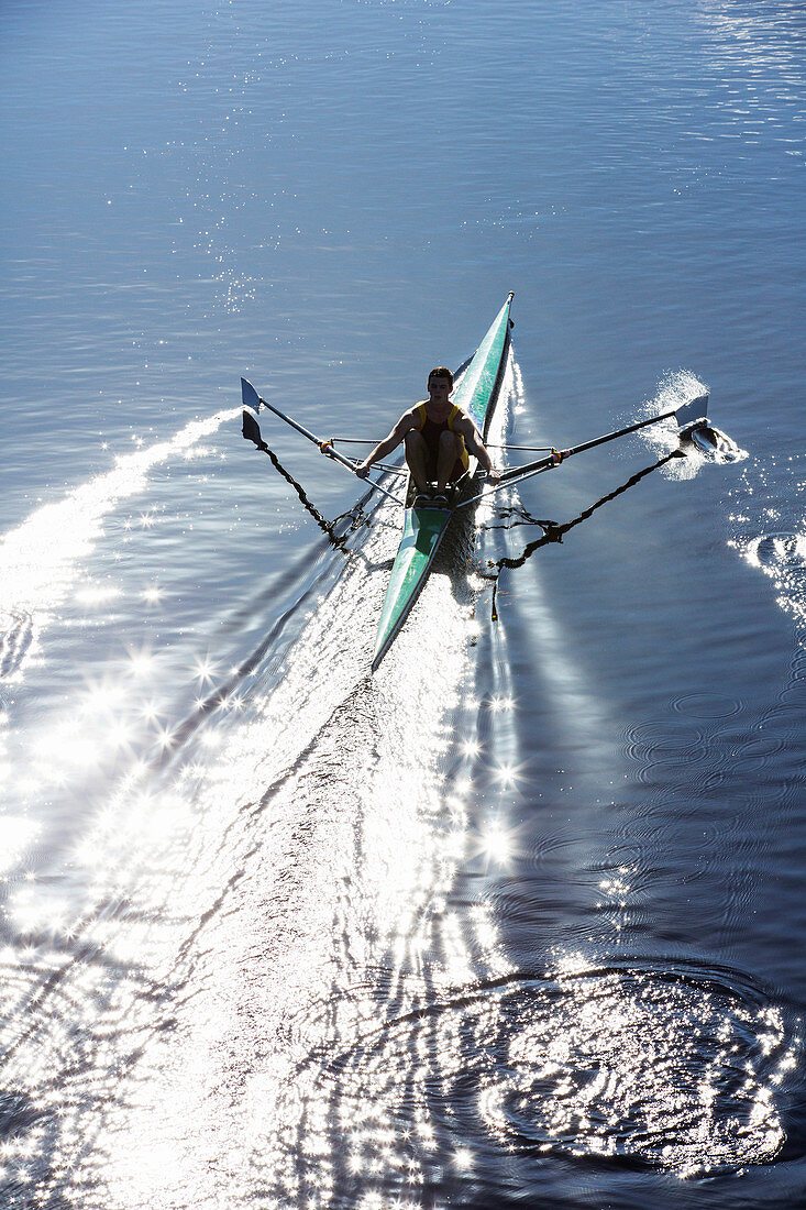 Man rowing scull on lake