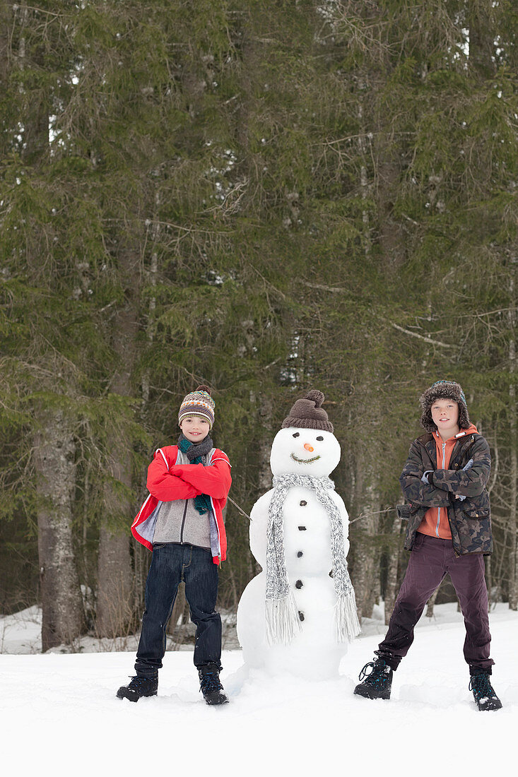 Boys next to snowman in woods