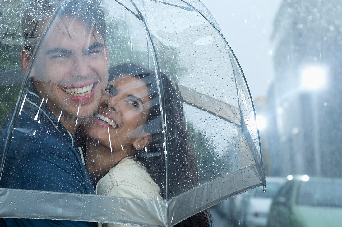 Happy couple hugging under umbrella