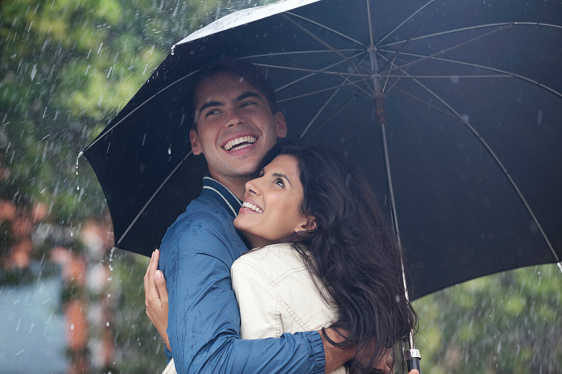 Happy couple hugging under umbrella