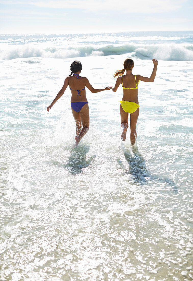 Friends in bikinis holding hands