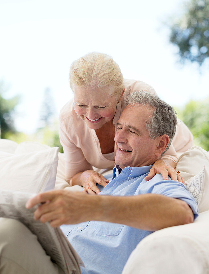 Senior couple reading newspaper sofa