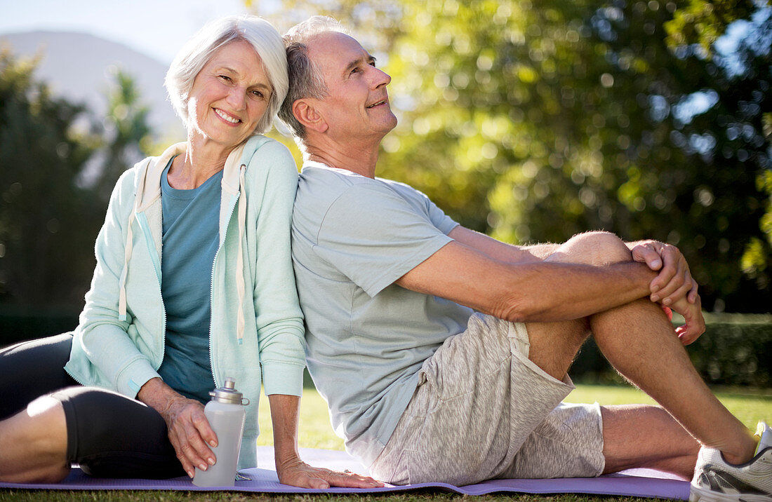 Senior couple sitting on yoga mat in park