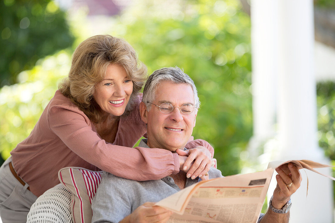 Senior couple reading newspaper on patio